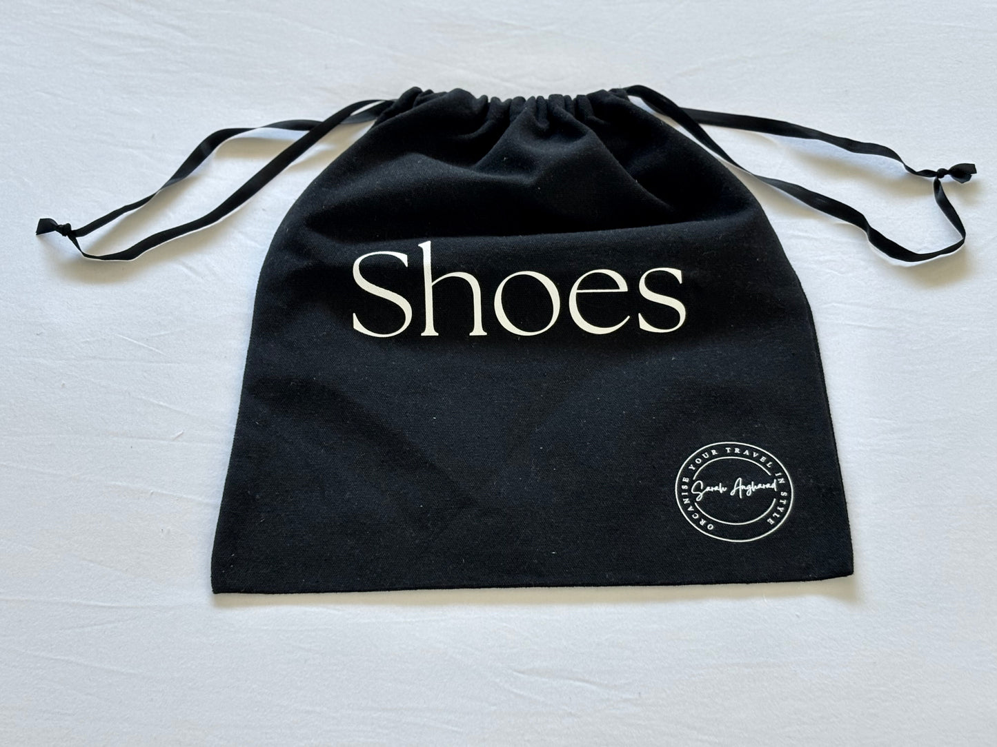 Black drawstring bag with 'Shoes' text and a logo on a white background