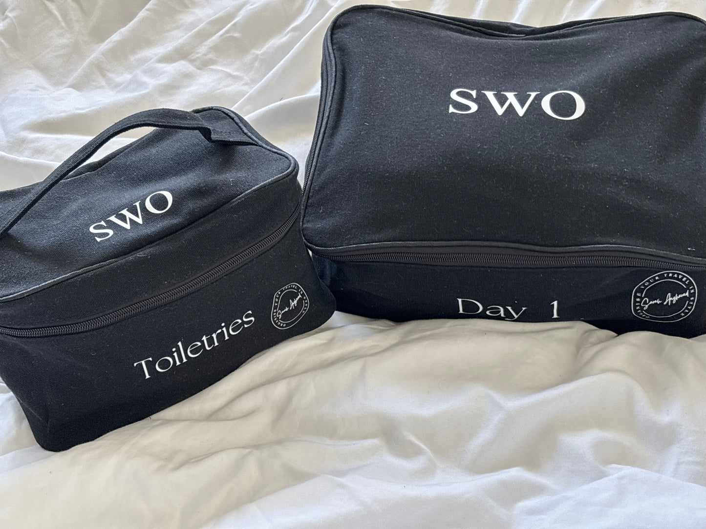 A black packing cube and toiletries bag, both personalised with initials