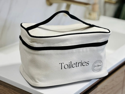 White toiletries bag with black trim on a bathroom counter
