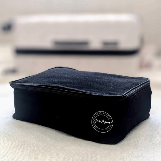 Black travel pouch with a logo on a light surface