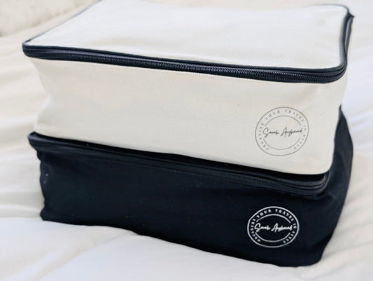 Two zipper pouches, one white and one black, with a brand logo on a light background.